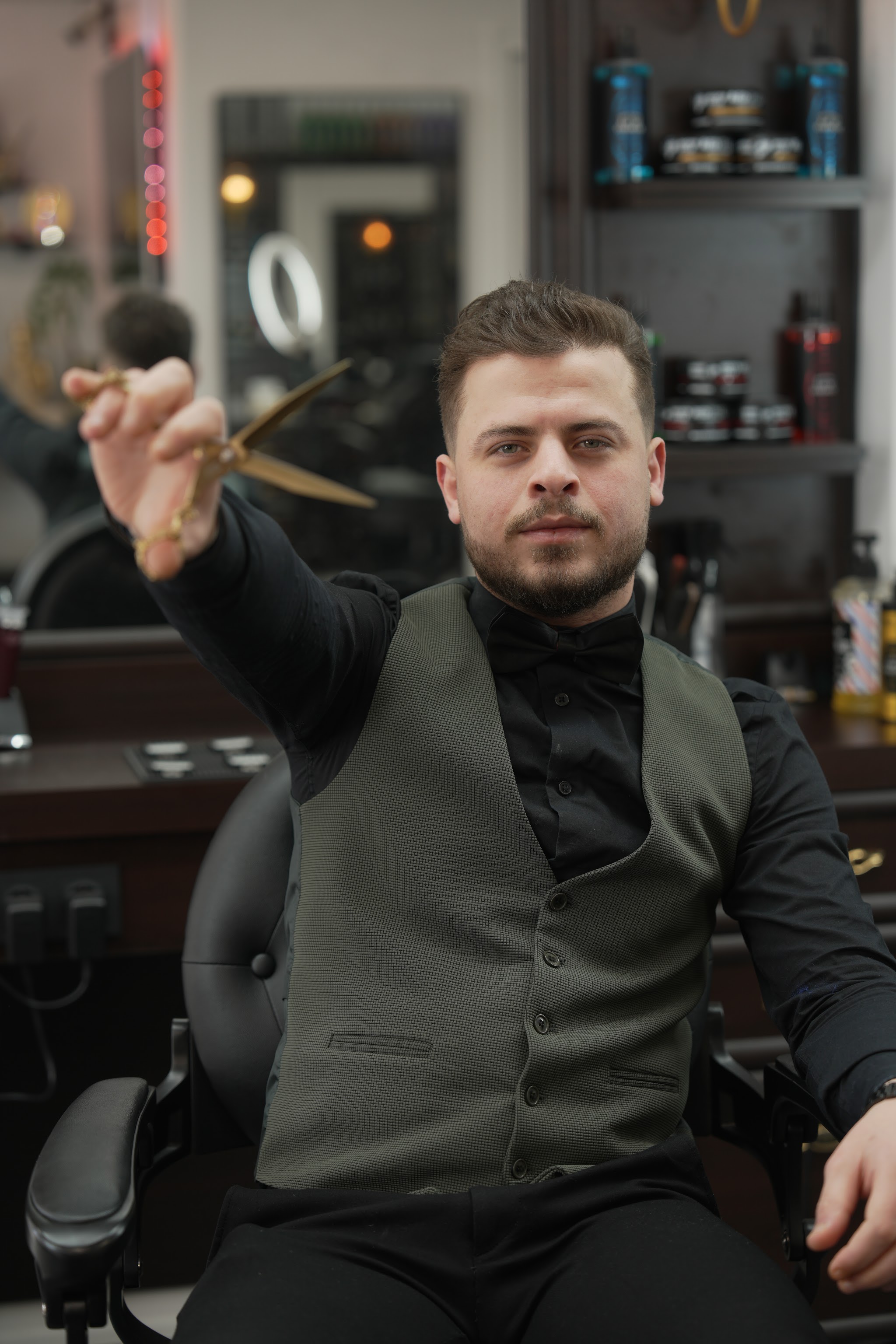 Een barbier in een donker gilet met een schaar in zijn hand, in de zaak